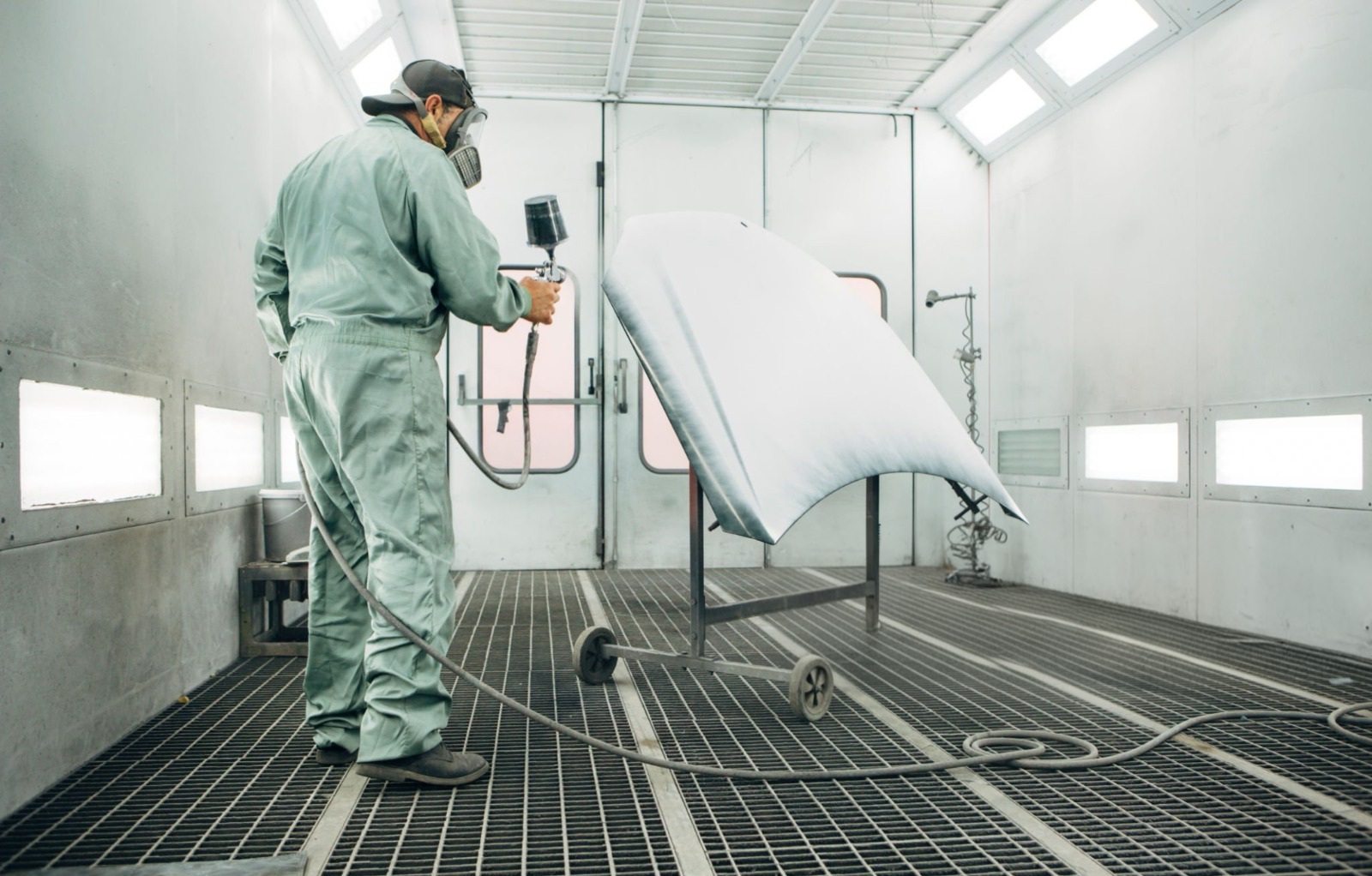 Technician spray painting a panel in the paint booth